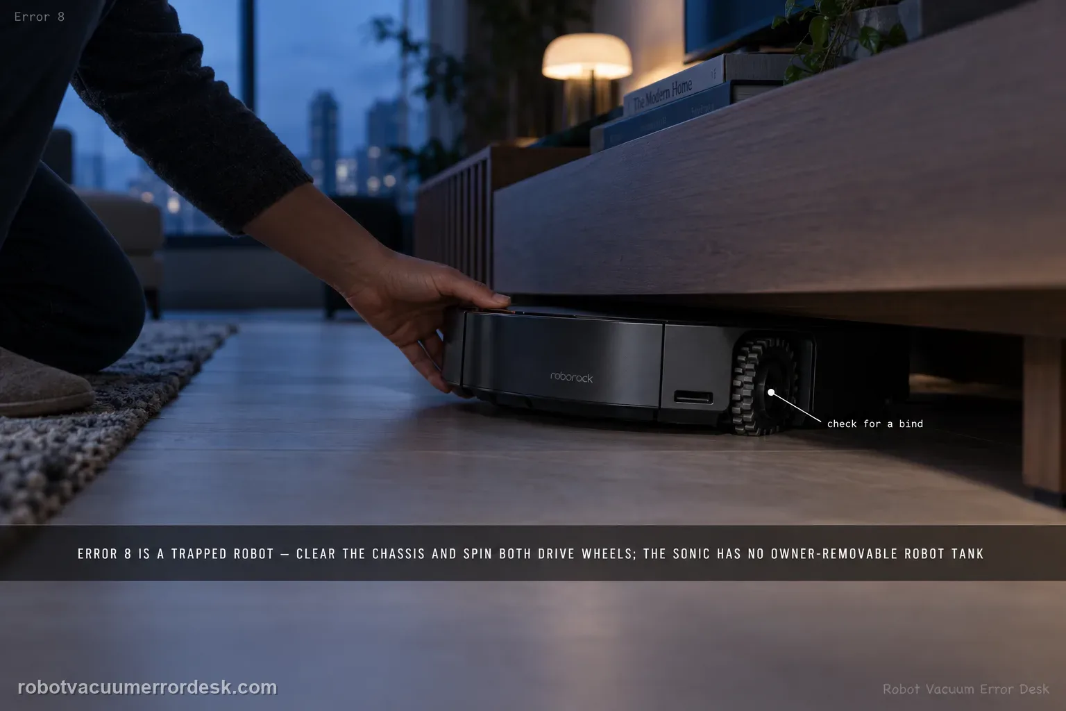 Low shot of a Roborock Saros 20 Sonic wedged under a media console at blue hour with cool dusk light from a large window and the room in shadow, a hand reaching in to free it, captioned that Error 8 is a trapped robot: clear the chassis and spin both drive wheels, and the Sonic has no owner-removable robot tank.
